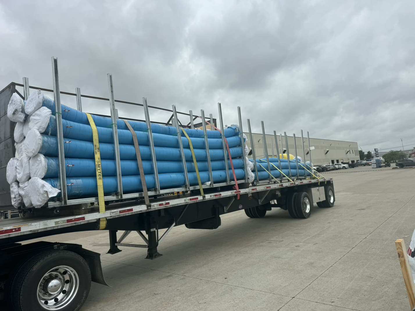 Flatbed loaded with blue pipe secured with straps