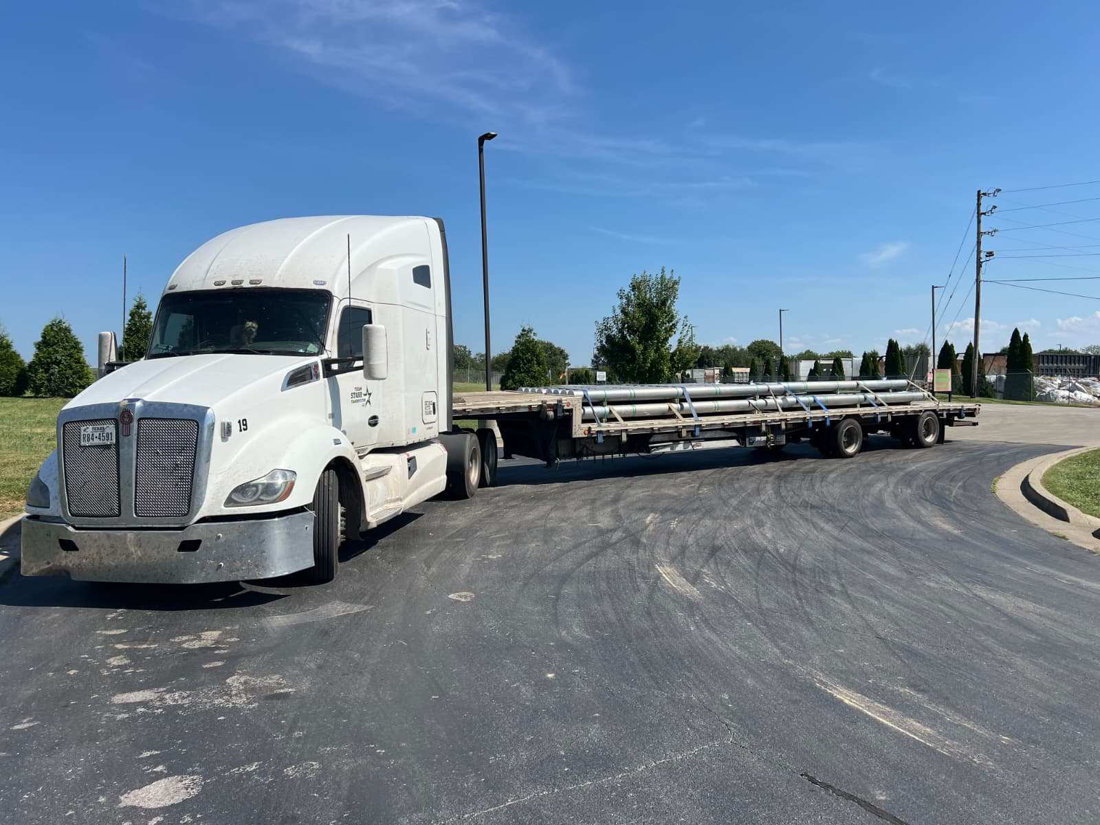 Team Starr Kenworth tractor hauling aluminum poles on a flatbed